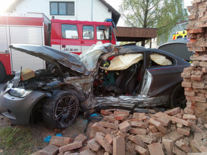 FOTO: Po nehodě zůstalo osobní auto zaklíněné v domě. Řidič se spolujezdcem jsou v nemocnici