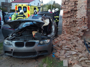 Po nehodě zůstalo osobní auto zaklíněné v domě. Řidič se spolujezdcem jsou v nemocnici