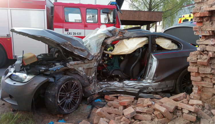 Po nehodě zůstalo osobní auto zaklíněné v domě. Řidič se spolujezdcem jsou v nemocnici