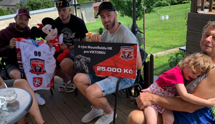 Hokejisté při předávání peněz, které vybrali mezi sebou