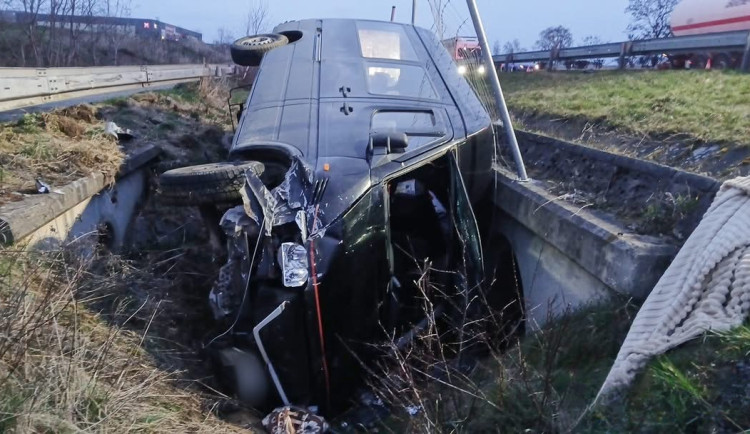 Mikrobus po střetu s osobákem vyletěl z dálnice, prorazil oplocení a skončil na boku
