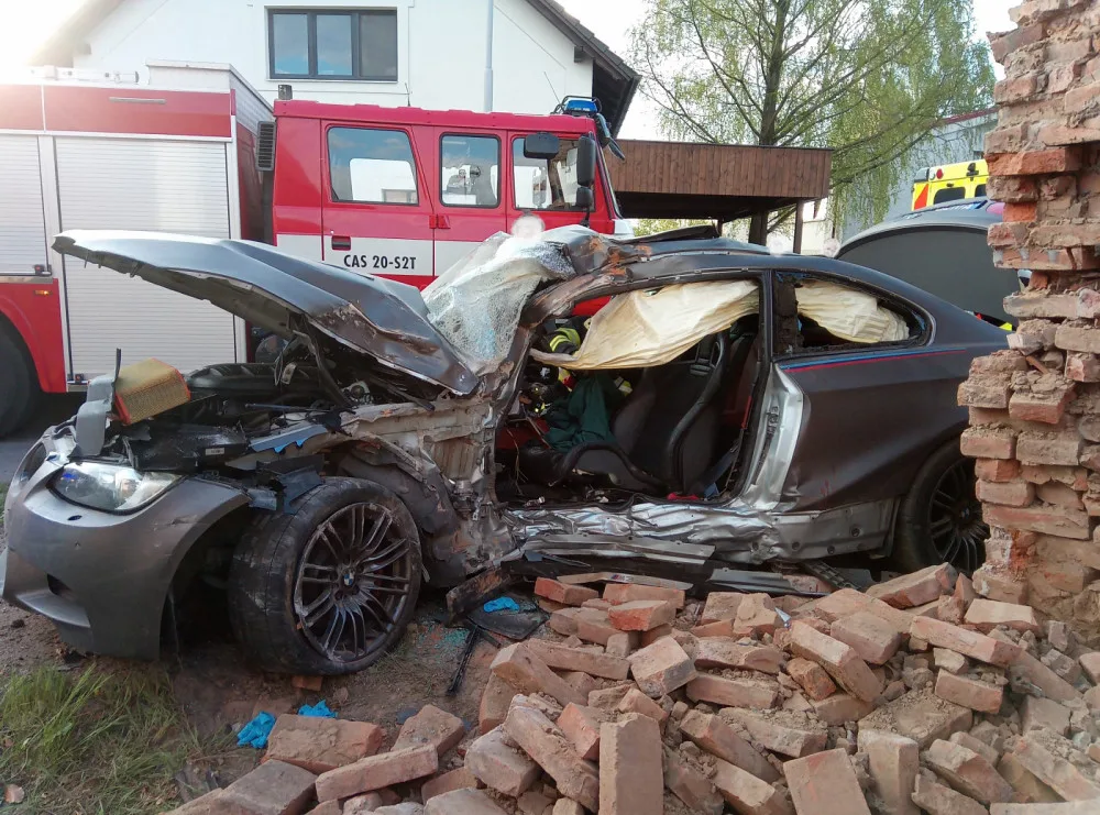 Po nehodě zůstalo osobní auto zaklíněné v domě. Řidič se spolujezdcem jsou v nemocnici