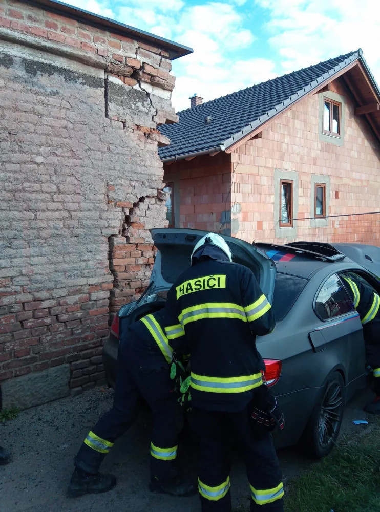 Po nehodě zůstalo osobní auto zaklíněné v domě. Řidič se spolujezdcem jsou v nemocnici