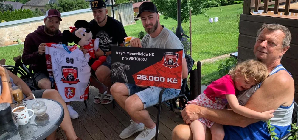 Hokejisté při předávání peněz, které vybrali mezi sebou