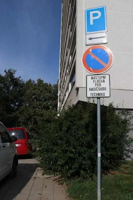 Špatně zaparkovaná auta u panelového domu