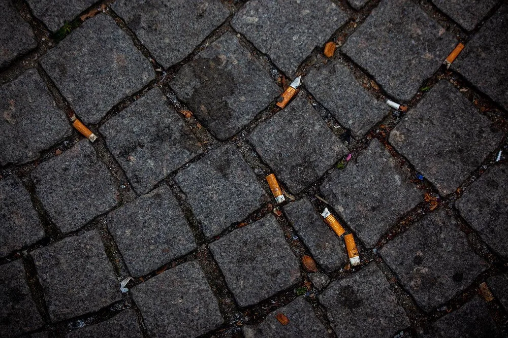 Nedopalky cigaret mezi dlažebními kostkami