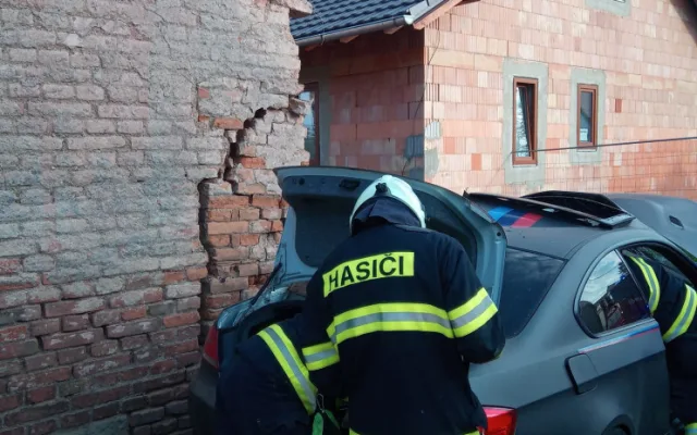 Po nehodě zůstalo osobní auto zaklíněné v domě. Řidič se spolujezdcem jsou v nemocnici