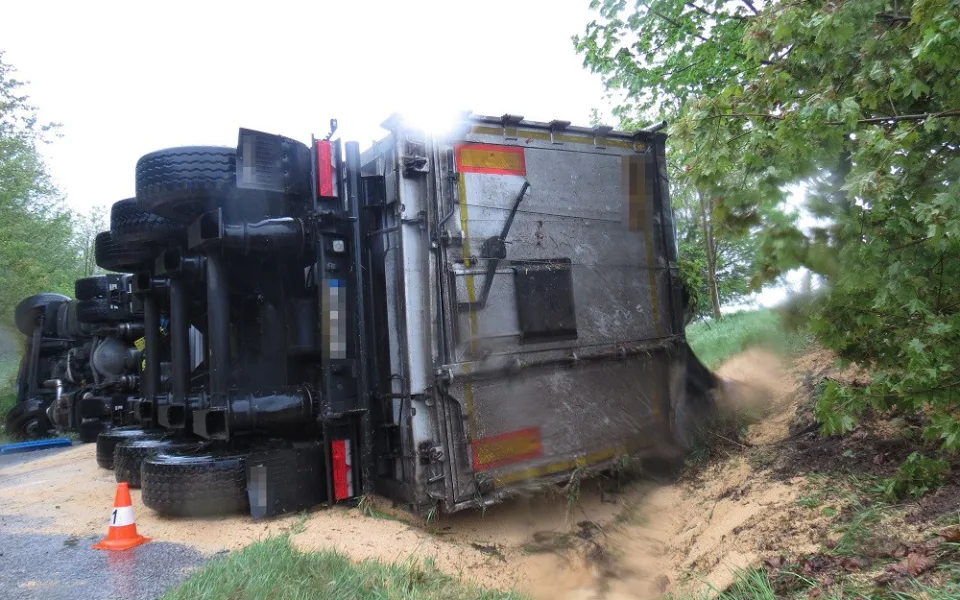 Kamion havaroval a skončil na boku. Krmný šrot, který vezl, zasypal vozovku