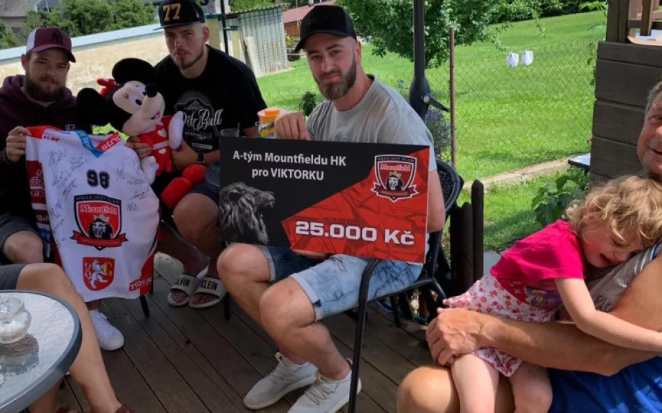 Hokejisté při předávání peněz, které vybrali mezi sebou